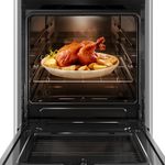 Foto frontal do fogão 4 bocas Continental prata automático com mesa compartimentada, modelo FC4CS- bivolt com a porta do forno aberta. Dentro dele, há luz interna na parte de cima e um frango assado com batatas em um refratário de vidro que está em cima de uma prateleira feita de grades, ela é removível e regulável em três alturas diferentes.