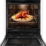 Foto-frontal-do-fogao-4-bocas-Continental-automatico-branco-com-mesa-de-vidro-modelo-FC4VB-–-bivolt-com-a-porta-do-forno-aberta.-Dentro-dele-ha-luz-interna-na-parte-de-cima-e-um-frango-assado-com-batatas-em-um-refratario-de-vidro-que-esta-em-cima-de-uma-prateleira-feita-de-grades-ela-e-removivel-e-regulavel-em-tres-alturas-diferentes.