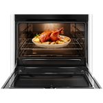 Foto frontal do fogão 5 bocas Continental automático, modelo FC5VB com a porta do forno aberta. Dentro dele, há luz interna na parte de cima e um frango assado com batatas em um refratário de vidro que está em cima de uma prateleira feita de grades, ela é removível e regulável em três alturas diferentes.
