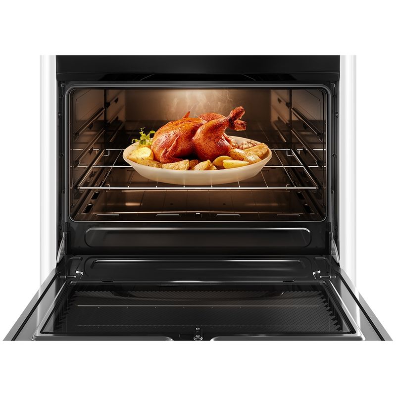 Foto frontal do fogão 5 bocas Continental automático, modelo FC5VB com a porta do forno aberta. Dentro dele, há luz interna na parte de cima e um frango assado com batatas em um refratário de vidro que está em cima de uma prateleira feita de grades, ela é removível e regulável em três alturas diferentes.